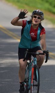 Barbara Schneider waves her right hand while competing in a cycling road race